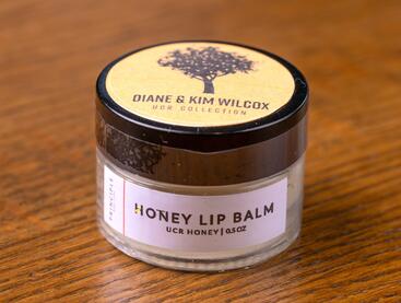 Jar of Honey Lip Balm on a wooden table.